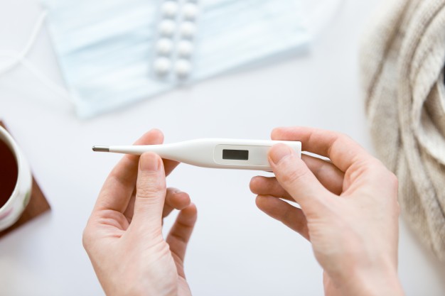female hands holding electronic thermometer over the white offic 1163 2725