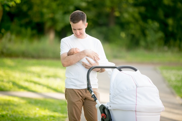 man standing with a baby in her arms in the park 1218 522