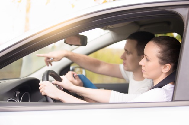 young woman driving man pointing the direction 1163 2670